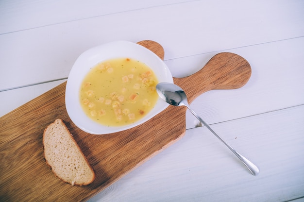 Foto caldo de sopa en un bol con pan sobre una mesa de madera.