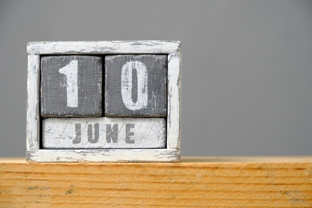 Calendario para el 10 de junio hecho de cubos de madera sobre un estante de fondo gris con un espacio vacío para el texto