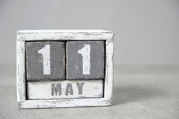 Calendario del 11 de mayo hecho con cubos de madera de fondo gris con un espacio vacío para el texto