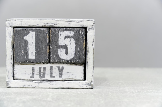 Calendario para el 15 de julio hecho de cubos de madera sobre fondo gris con un espacio vacío para el texto