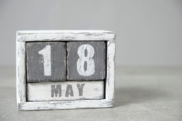 Calendario del 18 de mayo hecho con cubos de madera de fondo gris con un espacio vacío para el texto