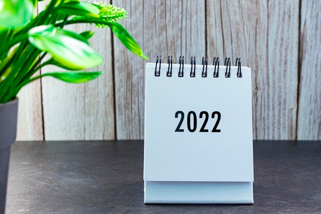 Calendario 2022 con planta en maceta sobre escritorio de madera. Concepto de año nuevo