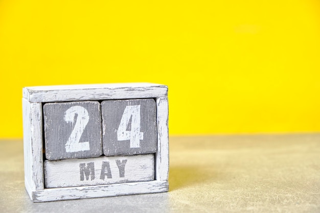 Calendario del 24 de mayo hecho con cubos de madera de fondo amarillo con un espacio vacío para el texto