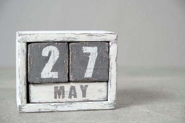 Calendario del 27 de mayo hecho con cubos de madera de fondo gris con un espacio vacío para el texto