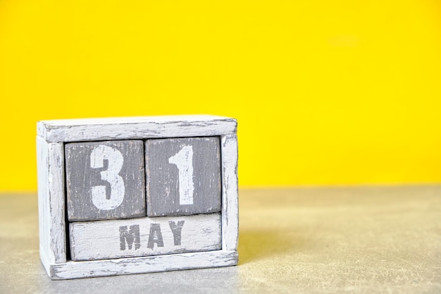 Calendario del 31 de mayo hecho con cubos de madera de fondo amarillo con un espacio vacío para el texto