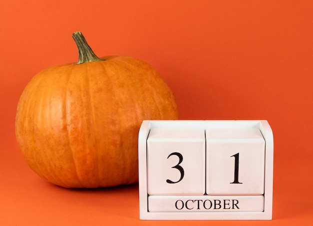 Foto calendario del 31 de octubre de halloween y calabaza sobre fondo naranja cartel de postal de fiesta navideña de otoño