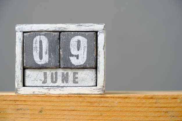 Calendario para el 9 de junio hecho de cubos de madera sobre un estante sobre fondo gris Con un espacio vacío para el texto Día de los amigos Día de los archivos Día de acreditación