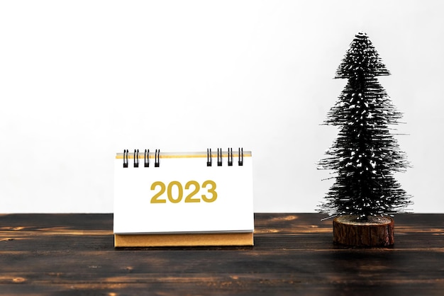 Calendario de año nuevo 2023 con pino en la parte superior del escritorio de madera