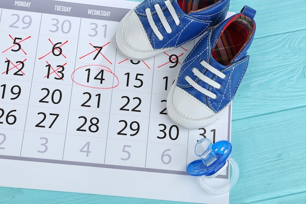 Foto calendario con botas de bebé sobre fondo de madera