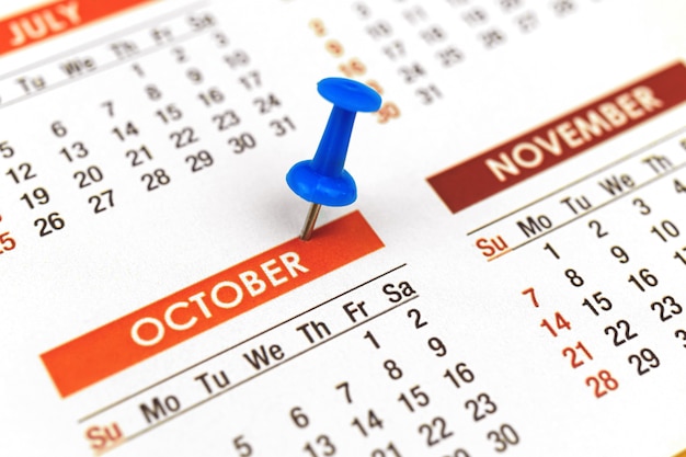 Calendário com alfinete, close-up do mês de outubro, conceito de planejador, foto de foco seletivo