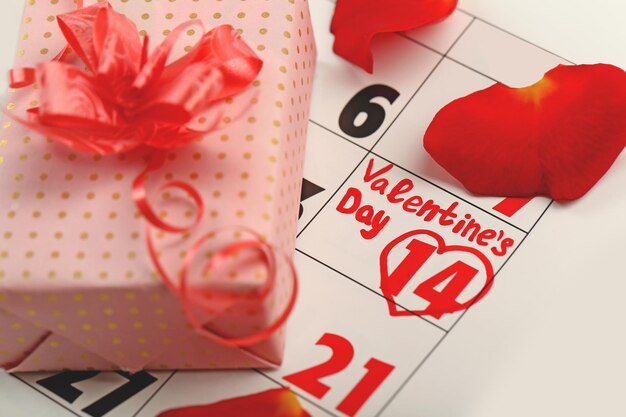 Calendário com data de 14 de fevereiro caixa de presente e conceito de dia dos namorados de pétalas de flores rosa