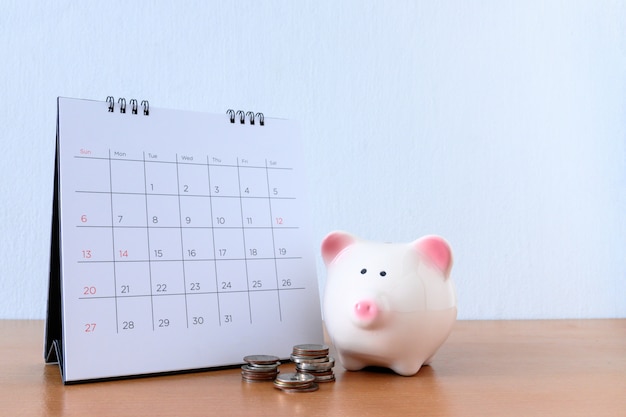 Calendário com dias e piggybank na mesa de madeira