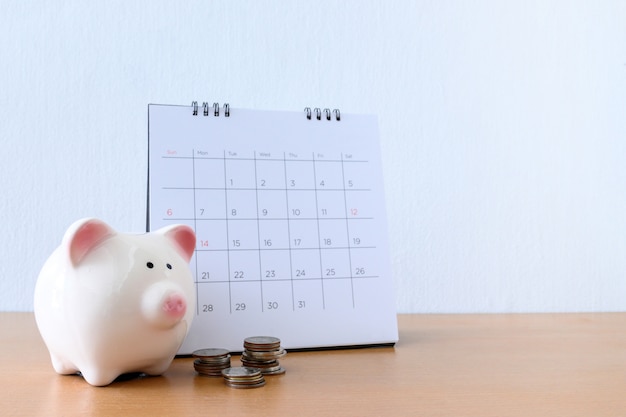 Calendário com dias e piggybank na mesa de madeira