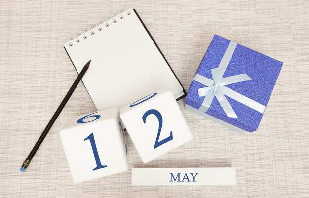 Calendário com texto azul na moda e números para 12 de maio e um presente em uma caixa.