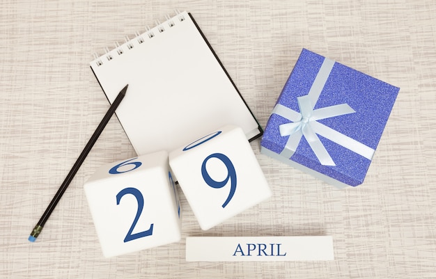 Calendário com texto azul na moda e números para 29 de abril e um presente em uma caixa.
