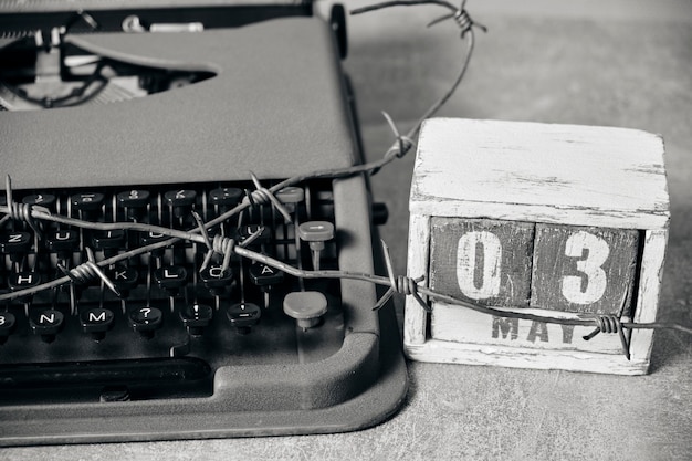 Calendário de 3 de maio e velha máquina de escrever embrulhada com arame farpadoConceito para o Dia da Liberdade de Imprensa