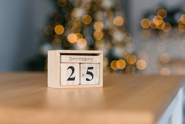 Calendário de blocos de madeira com a data de 25 de dezembro nas luzes de Natal. Clima de férias de inverno.