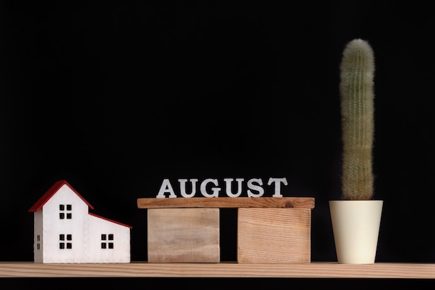 Calendário de madeira de agosto, modelo de cacto e casa em preto.
