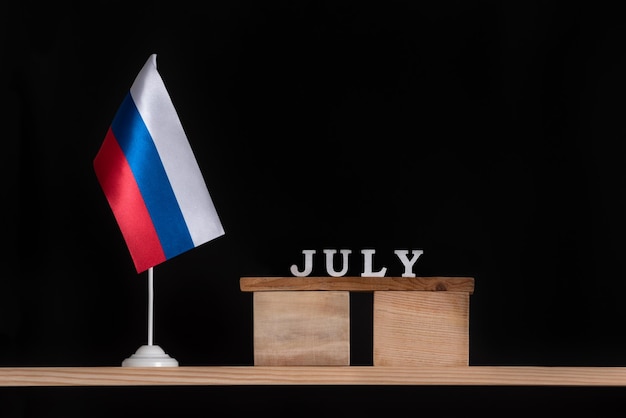 Calendário de madeira de julho com bandeira russa em fundo preto. Datas na Rússia em julho.