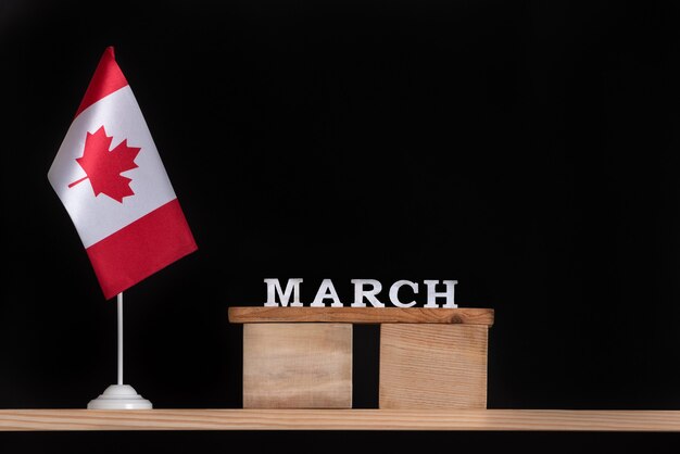 Calendário de madeira de março com a bandeira canadense em fundo preto. Férias do Canadá em março.