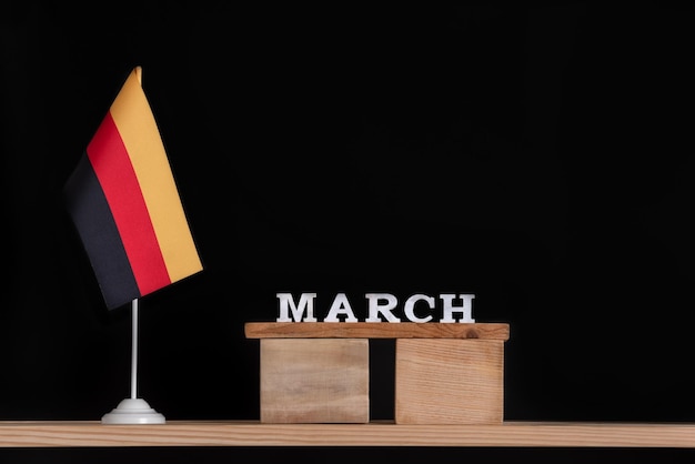 Calendário de madeira de março com bandeira alemã em fundo preto Datas na Alemanha em março