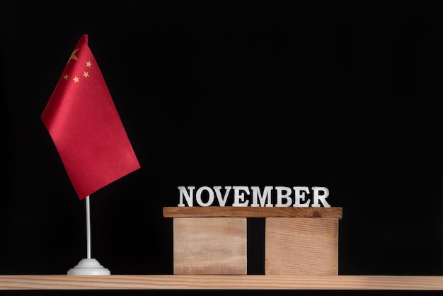 Calendário de madeira de novembro com bandeira chinesa em fundo preto Feriados da China em novembro