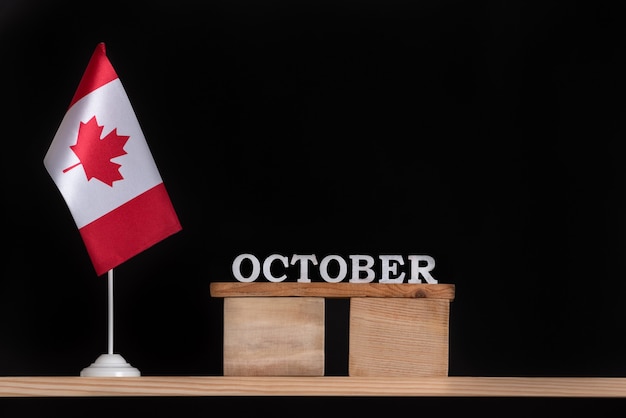 Calendário de madeira de outubro com a bandeira canadense na superfície preta. Férias de outono no Canadá.