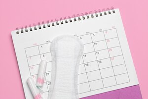 Calendário de menstruação calendário com almofadas e tampões em um fundo rosa