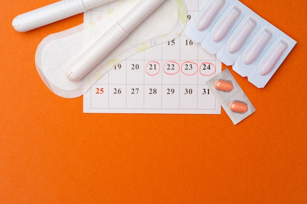 Calendário de menstruação com absorventes e absorventes internos, pílulas