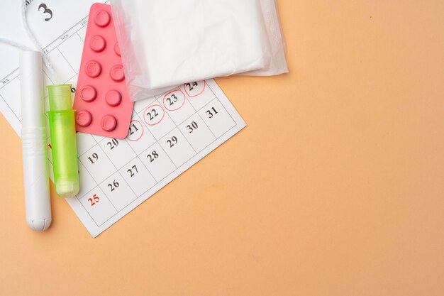 Calendário de menstruação com absorventes e absorventes internos, vista superior dos comprimidos