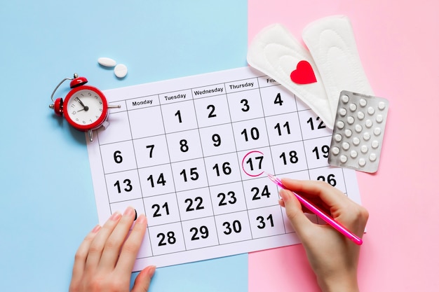 Calendário de menstruação com almofadas, despertador, pílulas anticoncepcionais hormonais