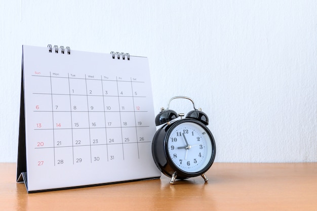 Calendario con días y reloj en mesa de madera