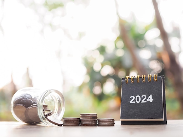 Foto calendario de escritorio de 2024 y pila de monedas el concepto de ahorrar dinero inversión financiera y negocios creciendo en el año 2024