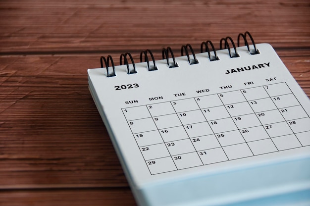 Foto calendario de escritorio blanco de enero de 2023 sobre fondo de mesa de madera concepto de calendario