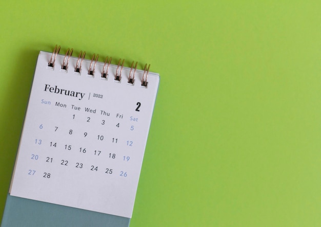 Calendario de escritorio para febrero de 2022 sobre un fondo verde