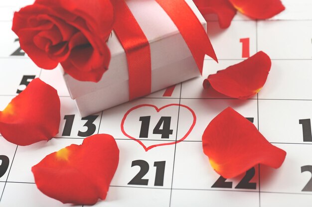 Calendario con fecha del 14 de febrero, caja de regalo y pétalos de rosa, concepto de día de San Valentín