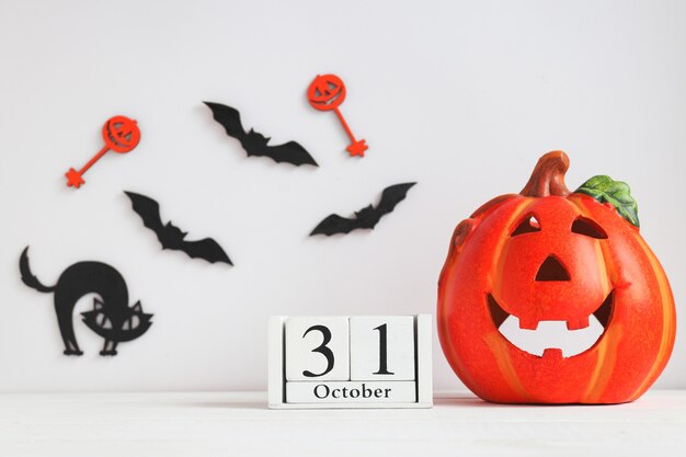 Calendario de fecha 31 de octubre Jackolatern gato negro y murciélagos en mesa blanca Tarjeta de Halloween