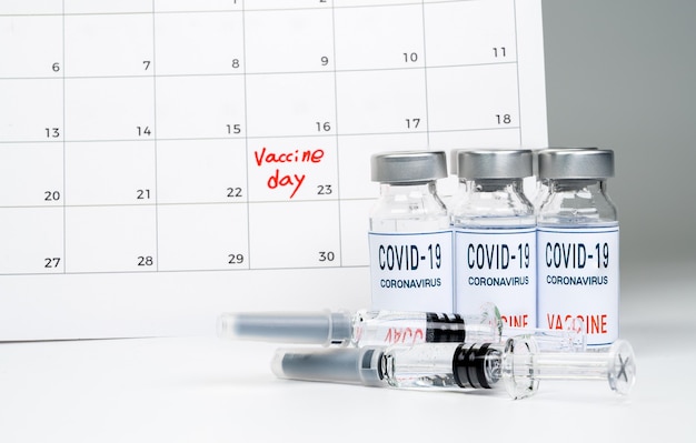 calendario con fechas de vacunación, una vacuna Covid-19 y un concepto médico con una jeringa.