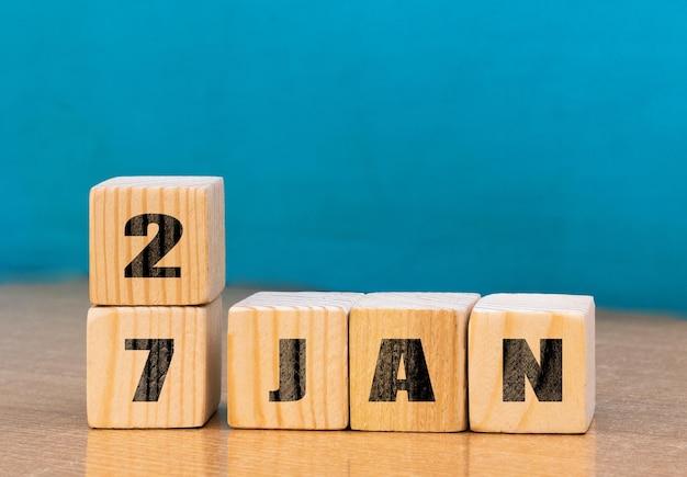 Calendario en forma de cubo para el 27 de enero sobre superficie de madera con espacio vacío para el calendario textcube para enero sobre fondo de madera