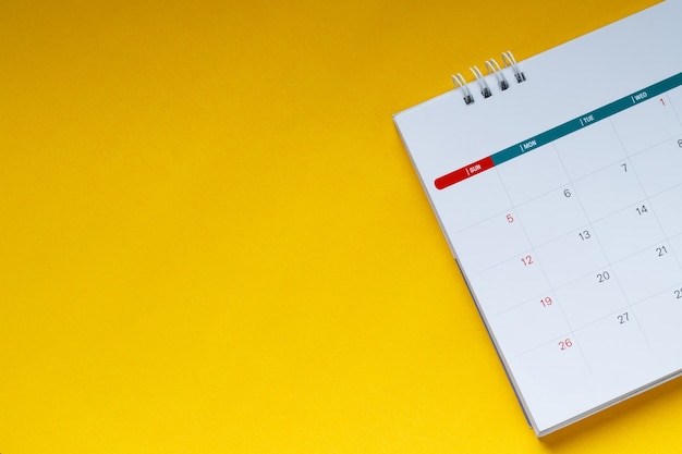 Calendario limpio blanco sobre fondo amarillo con espacio de copia