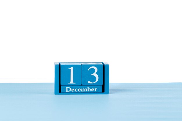 Calendario de madera el 13 de diciembre sobre un fondo blanco.