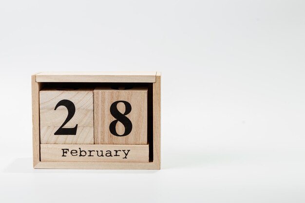 Calendario de madera el 28 de febrero sobre un fondo blanco.