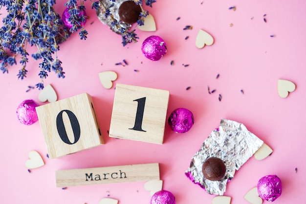 Calendario de madera con la fecha del 1 de marzo sobre un fondo rosa, un lugar para una inscripción, El primer día de primavera, una rama seca de lavanda