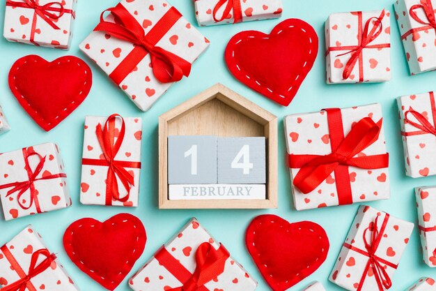 calendario de madera rodeado de cajas de regalo envueltas con cintas y corazones textiles