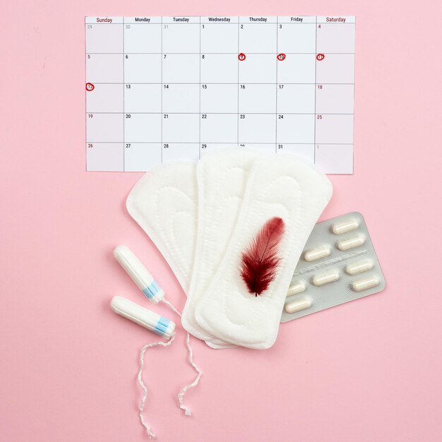 Calendário menstrual mulher almofadas tampões e pílulas para dor menstrual deitado em fundo vermelho Imagem