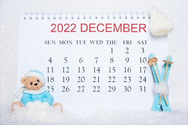 Calendario para el mes de diciembre de 2022 Cuaderno con fechas de calendario y un juguete Oso de peluche con ropa azul esquís azules sombrero blanco sobre nieve blanca Calendario para el mes de invierno Hola diciembre