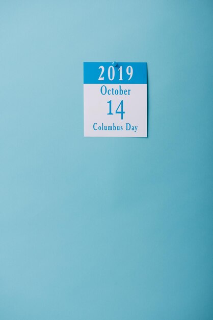 Foto calendario de papel blanco con la inscripción del día de colón aislado en azul