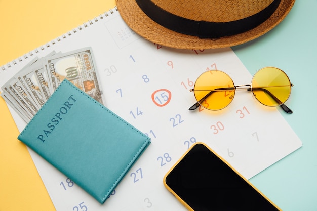 Calendario con pasaporte, gafas de sol y smartphone en azul amarillo