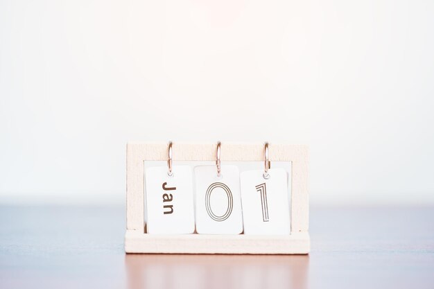 Un calendario que muestra la fecha del 1 de enero está en una mesa de madera