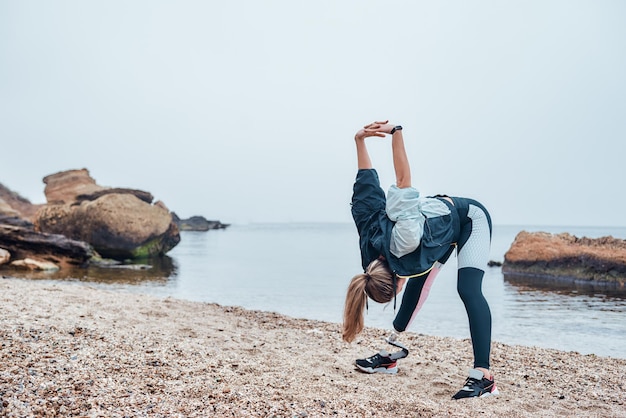 Calentamiento antes de entrenar fuerte atleta discapacitado mujer insportswear con prótesis de pierna haciendo